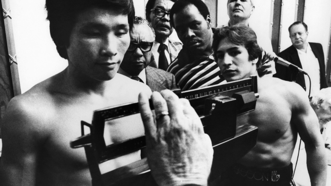 Ray Mancini watches on as challenger Duk Koo Kim weighs in for their championship fight in Las Vegas, Nov. 12, 1982.